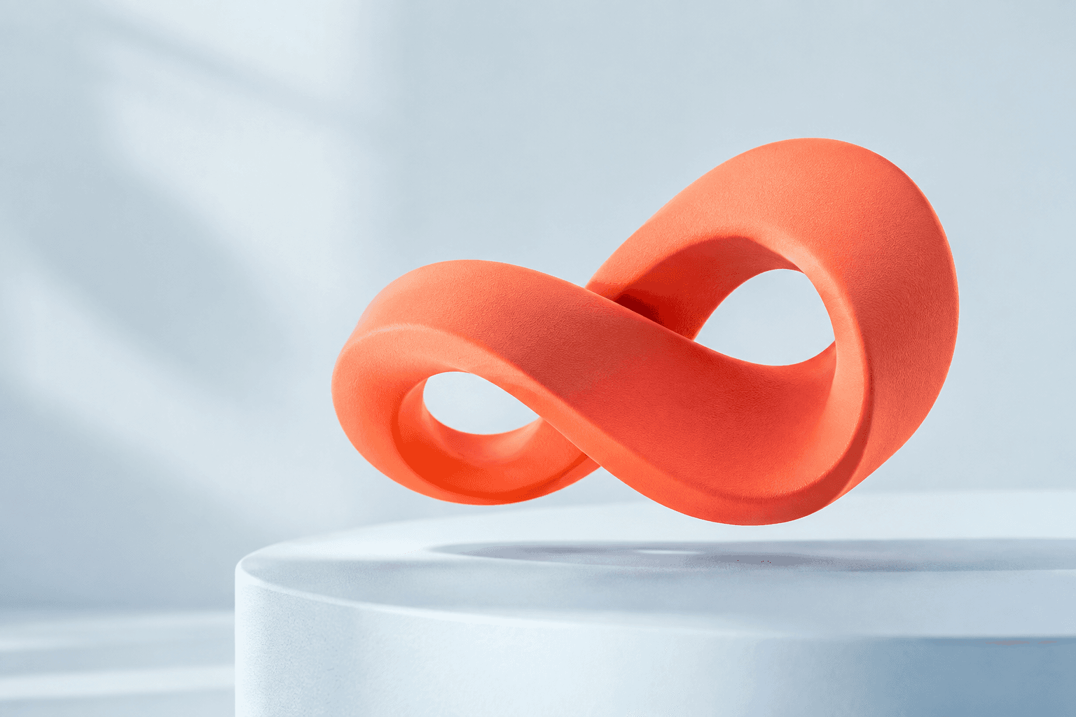 Sculptural coral ribbon on a pale blue studio surface